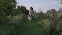 Woman running barefoot through field of flowers in summer sunset - wild and free