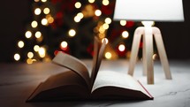 Book open on a table in Christmas time with pages that flip through the wind