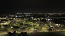 Drone flies over Convention Center Ulysses Guimarães toward Castelinho do Parque da Cidade at night in Brasilia, Brazil