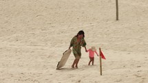 Mother walks daughter and sand board up sand dunes in summer day - Brazil fun activity