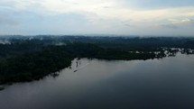 Aerial shot drone flies up and away from canoe boat on lagoon in middle of Amazon rainforest just before sunset