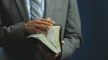 Religous Pastor Holding Bible In Hand Grey Blue Suit 