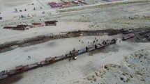 Aerial shot drone flies up and away in spiral over train cemetery in middle of desert