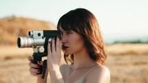 Pretty girl with vintage 8mm camera in the countryside