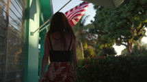 Woman walking into home at night touches american flag as she arrives - patriotism