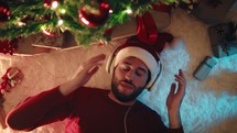 Happy man listening to music under the Christmas tree