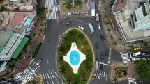 Aerial shot drone camera pans up from blue traffic roundabout to central park in downtown