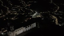 Drone flies over Church of Saint Francis of Assisi toward Igreja de Nossa Senhora das Mercês e Perdoes at night