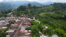 Aerial shot drone slowly ascends over main square looking at mirador on hill next to town