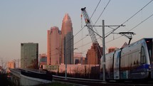 Commuter train on overpass with nearby crane near downtown Charlotte North Carolina