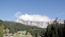 Dolomite mountain with clouds time lapse with rustic buildings