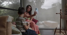 Trendy young mom with kids sitting in trendy cottage taking selfie - travel influencer