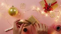 Girl Decorates Christmas gift boxes on pink background flat layer