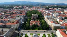 Aerial shot drone lowers behind art pavilion with downtown Zagreb, Croatia in the distance