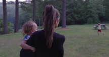 Mother walking with daughter and young son in forest campgrounds - summer vacation