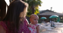 Grandmother bouncing grand daughter in arms outdoors in tropical location at sunset