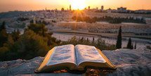 Bible open looking out towards Jerusalem Old City, Israel from the viewpoint of Mount of Olives with Copy space at Sunset