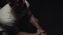 tattooed male praying in a dark room 