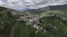 Drone flies to the right over community on side of hill in Brazilian countryside on cloudy afternoon
