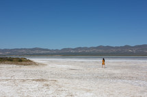 a woman in a dress walking in the desert 