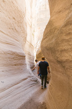 men walking through narrow openings between rocks 
