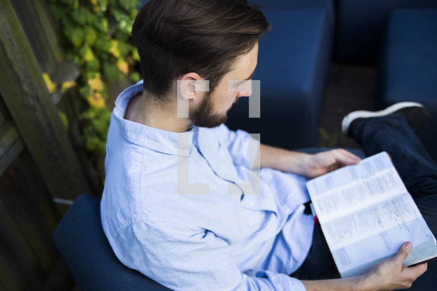 a man reading a Bible in his backyard 