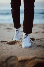 a man wearing shoes walking on a beach 