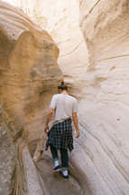 a man hiking through a narrow crack between rocks 