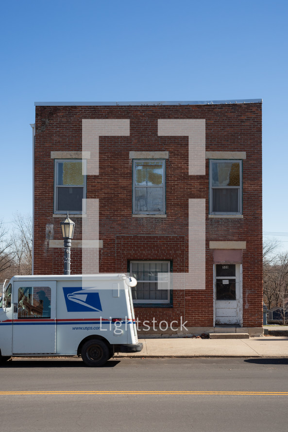 Post office truck in front of red brick building in small town