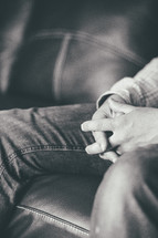 praying hands in a man's lap 