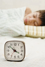sleeping boy next to an alarm clock 
