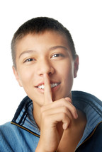 Smiling boy with finger on his lips