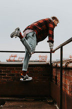 a man in a plaid shirt on a rooftop deck 