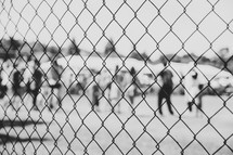 view of people through a chain link fence 