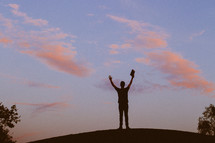 silhouette of a man with raised hands holding a Bible 