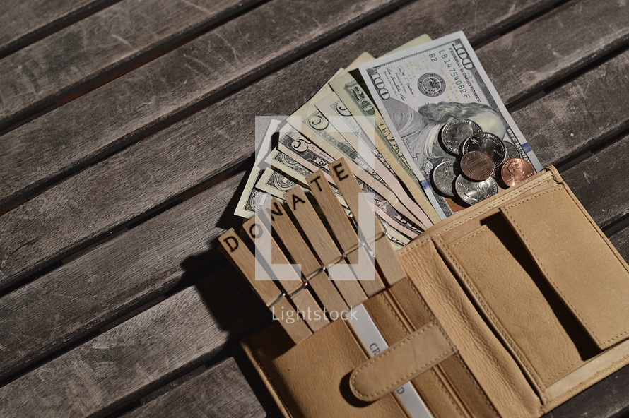 Open purse with money flowing out attached to wooden clothespins with the word DONATE burnt into. 