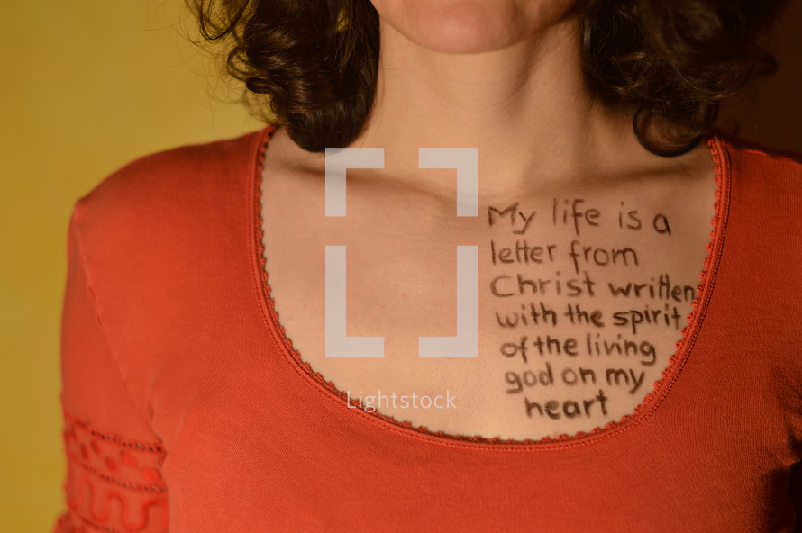 A woman with a scripture written on her chest in ink.
