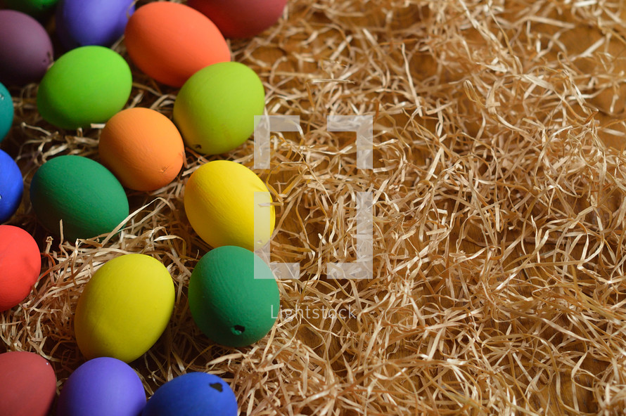 Colorful Easter eggs on a bed of straw.