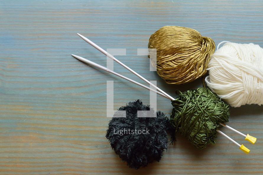balls of yarn and knitting needles on a cyan table