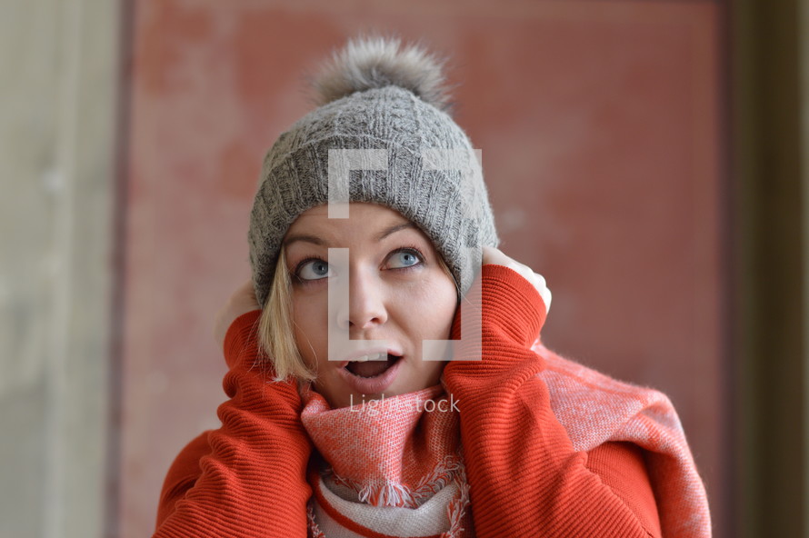 a woman in a beanie looking surprised 