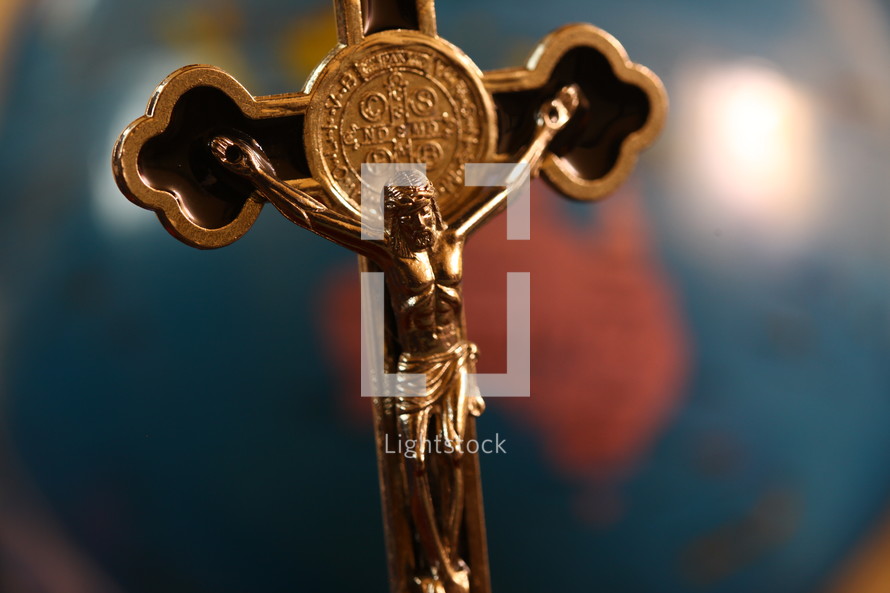 silver crucifix necklace on a globe