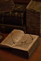 old dusted antique books with reading glasses