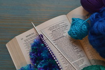 wool and a piece of knitting on a bible open at the page of Proverbs 31: The Wife of Noble Character with the line: She selects wool and flax underlined