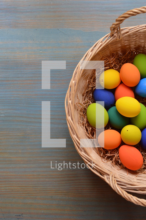 Easter eggs in a basket on cyan wood 