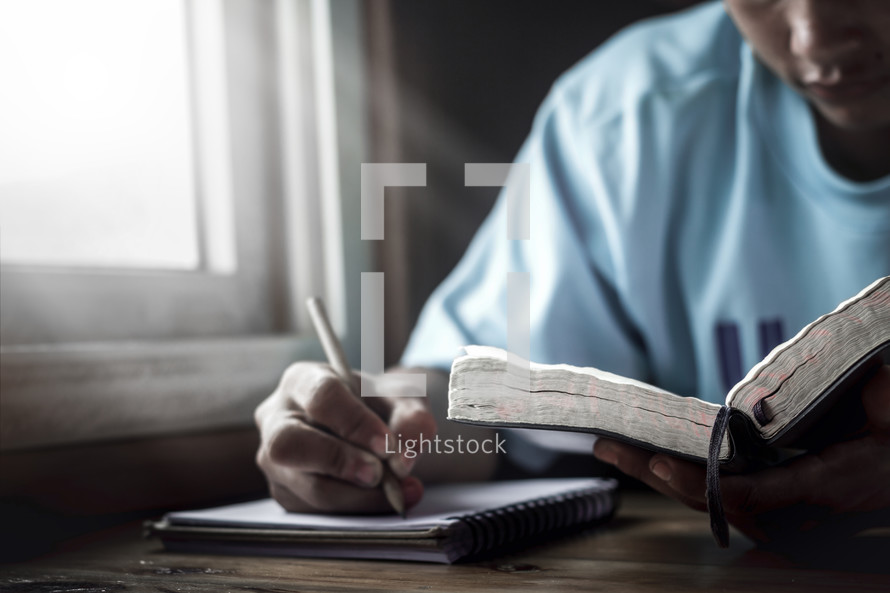 a man reading a Bible and taking notes 