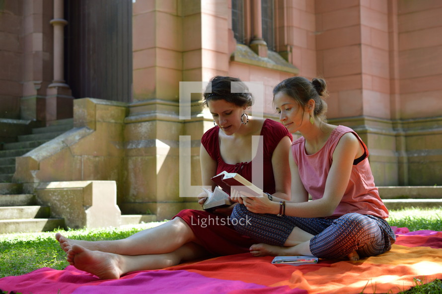 friends reading Bibles together outdoors next to a cathedral 