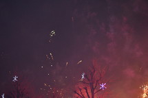 Illuminated sky and smoke from the fireworks. 
firework, fireworks, new year, eve, New Year's Eve, party, celebrate, celebration, celebrating, night, colors, colorfully, colorful, bright, shining, shine, explode, exploding, explosion, sky, nite, pyrotechnic, flame, flames, sparks, sparkling, spark, sparkle, sparklers, fire, light, burst, bursting, smoke, July 4th, fourth of July, 4th of July, Independence Day, Memorial Day, Labor Day, ceremony, festival, illumination, illuminate, tree, trees, red, purple, star, stars, yellow, orange, pink, clouds