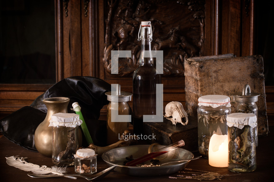 vintage Apothecary - or:
eerie witches' kitchen with lot of ingredients for a potion and ancient gruesome jars dark with only candlelight for Halloween