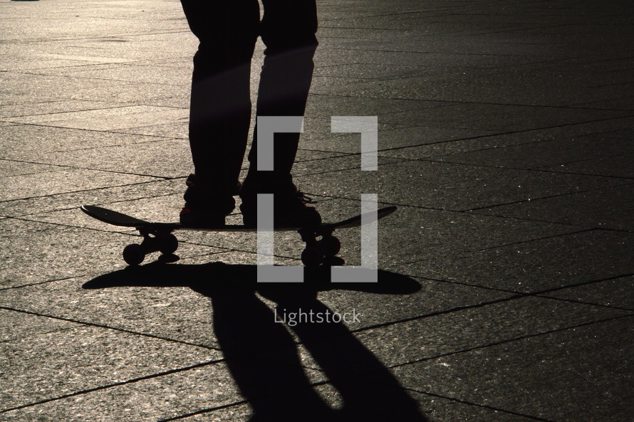 skater jumping on his skateboard with his shadow in evening backlight.
