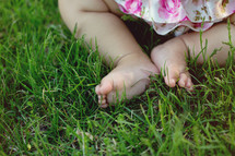 A baby's feet in green grass.